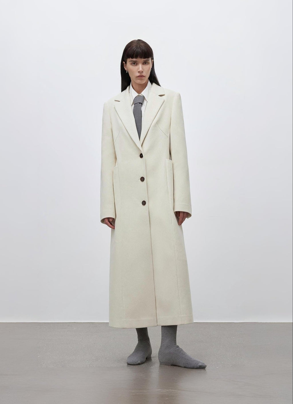 Person wearing a long white coat on a plain background