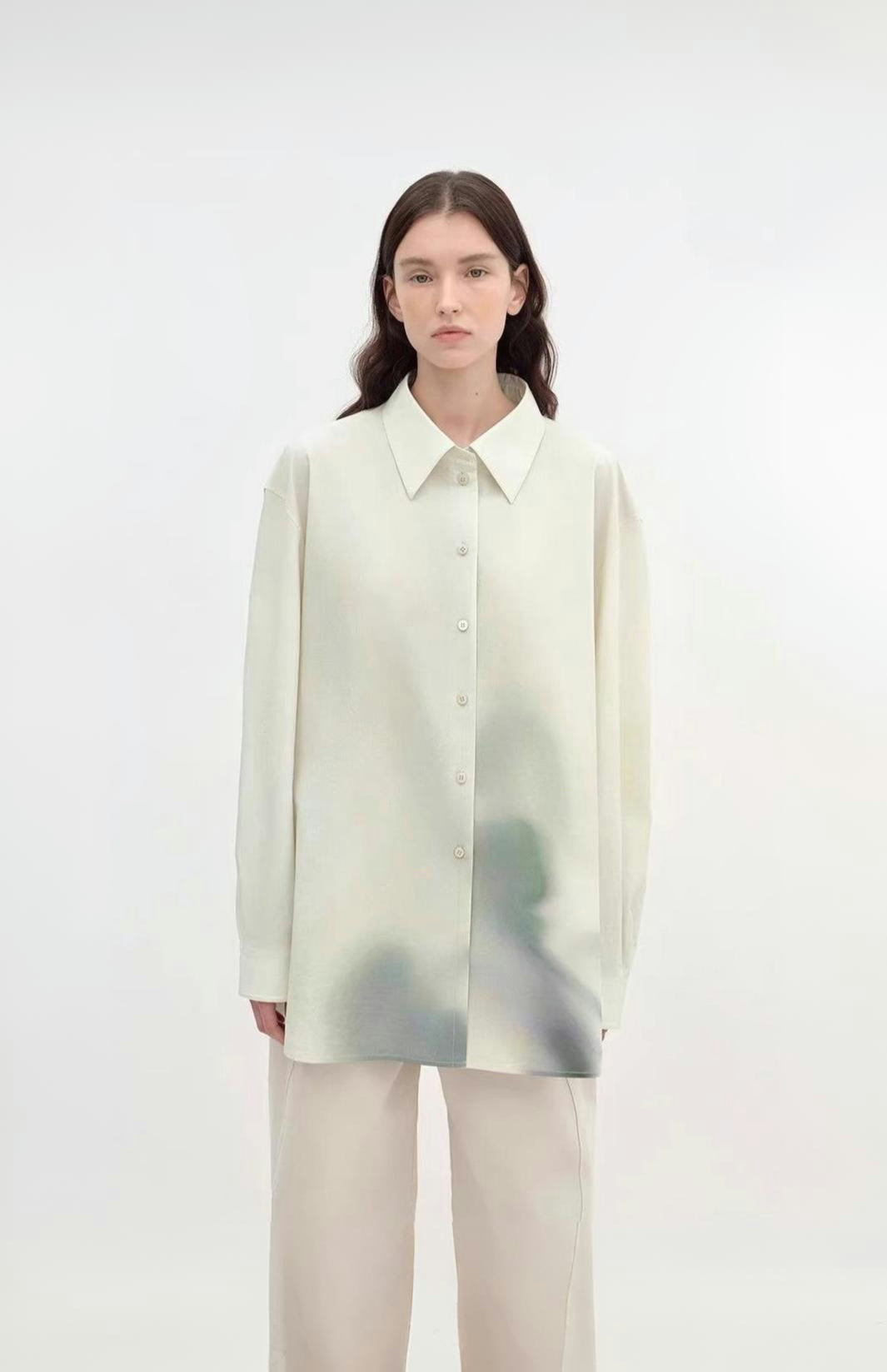 Person wearing a light-colored shirt with a subtle pattern on a white background