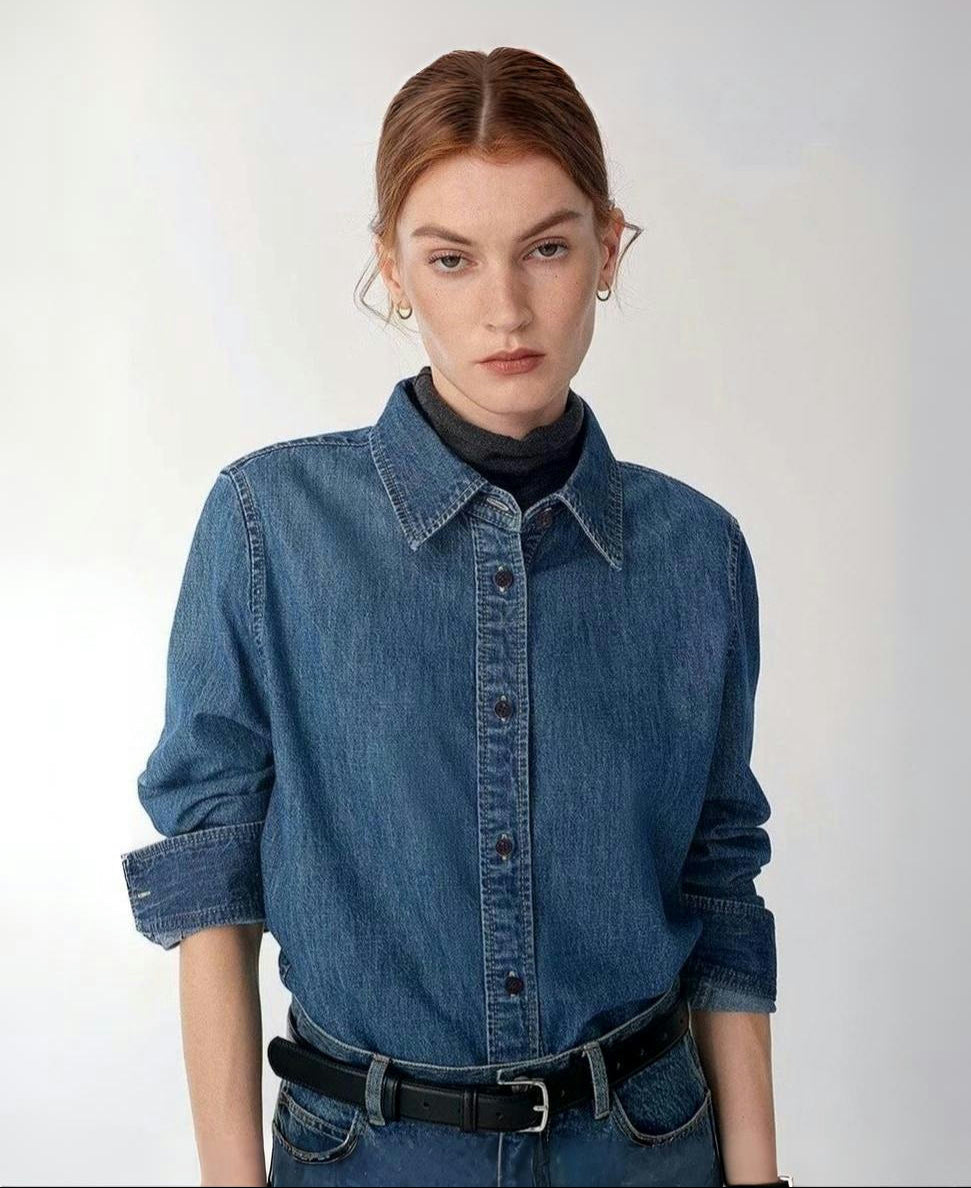 Woman wearing a blue denim shirt with a plain background